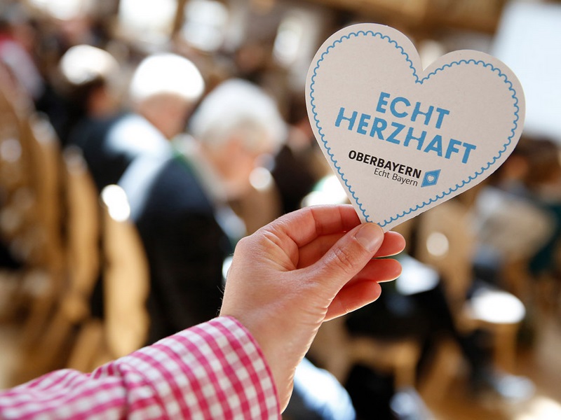 Hand hält Bieruntersetzer mit "Echt herzhaft"