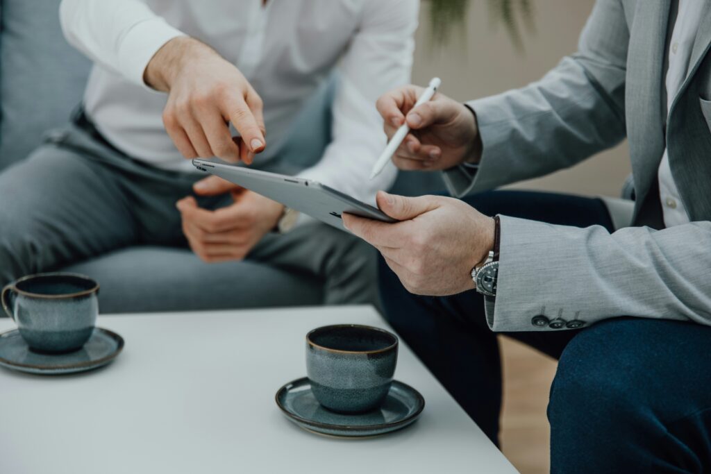 Zwei Männer sitzen am Tisch mit dem Tablet und Kaffee
