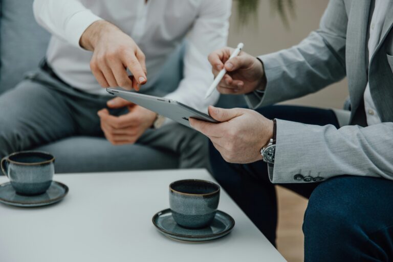 Zwei Männer sitzen am Tisch mit dem Tablet und Kaffee